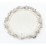 A late Victorian silver salver, ornate scrolling foliate and rocaille raised border, on three scroll