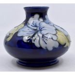 Moorcroft Pottery: A Moorcroft 'Hibiscus' pattern squat vase on blue ground. Height approx 10.5cm.