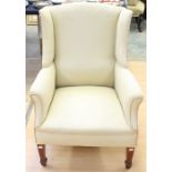 An Edwardian cream upholstered wing chair, raised on square tapered legs *** Provenance: from the