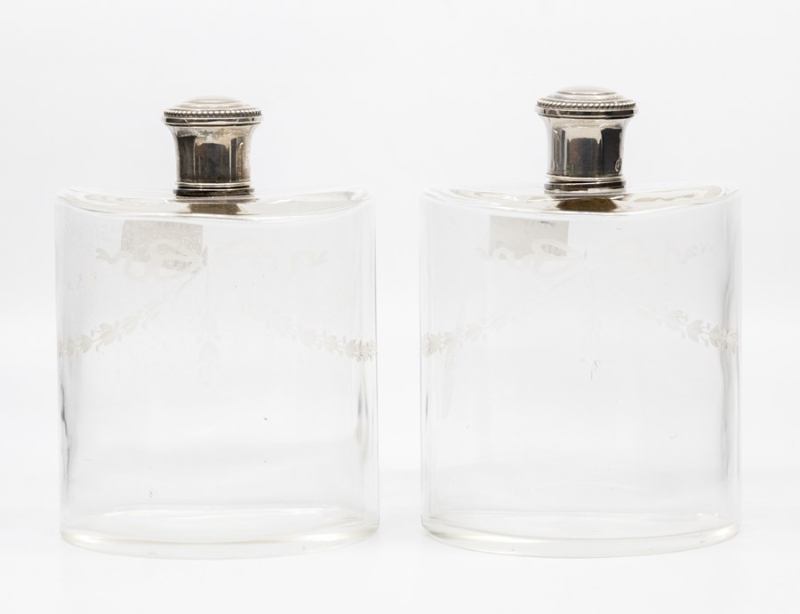 Two early 20th Century French glass etched semi-elliptical spirit bottles with stoppers and silver