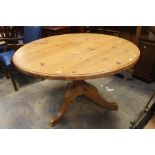 A contemporary pine dining table, raised on a pedestal base, 77cm high, 127cm in diameter, with a