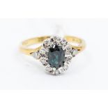 A sapphire and diamond set 18ct gold cluster ring, oval sapphire claw set to the centre within a