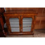 A Victorian walnut and marquetry pier cabinet, fitted with two glazed doors enclosing shelves,