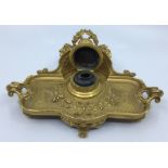 A 19th Century ormolu shape rectangular inkwell on stand, the raised back with central shell motif