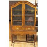 A Queen Anne style walnut glazed bookcase, dome topped, fitted with two glazed doors enclosing three