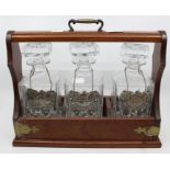 A 20th Century three glass decanter Tantalus with key and white metal name tags in mahogany