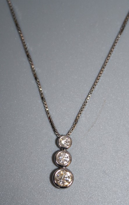 A three stone diamond pendant, the graduated vertically set cut diamonds in collar mounts to a box