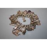 A 20th century silver charm bracelet affixed with 33 charms: dolphin, tennis racket, thimble,