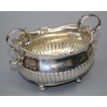 A Geo III  silver two handled boat form sugar bowl with cast shell and gadrooned rim. Raised on four