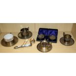 Three French white metal tea cups and saucers, one decorated in shallow relief with mistletoe,