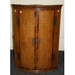 A 19th century oak mahogany cross banded barrel fronted hanging corner cupboard. 95 x 68cm