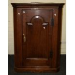 A 19th century oak hanging corner cupboard with arched fielded panel door. 116 x 82 cms.