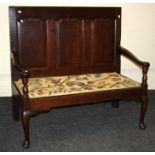 A George III oak settle, probably Shropshire, the shaped fielded three panel back over downswept