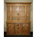 A 19th century stripped pine tall dresser, the top with arch barred glazed doors enclosing 3 shelves