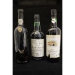 A bottle of Taylors select; two other bottles of tawny port. Two bottles have heavily soils to