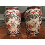 A pair of late 19th Century Japanese imari baluster vases, each decorated with cartouche panels of