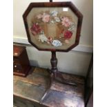 A 19th Century polescreen with a woolwork floral panel on a tripod base, height 148cm