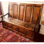 A George III joined oak settle, circa 1770, the back support with five moulded panels above a hinged
