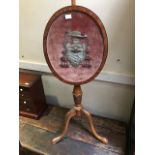 A 19th Century satinwood polescreen, oval panel containing a raised bullion work and tassel heraldic