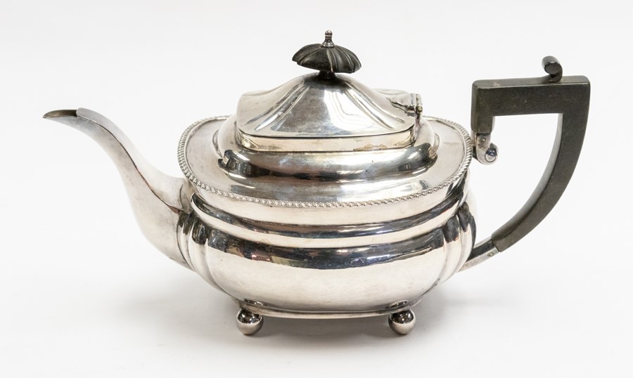 A Georgian style silver teapot, ebonised final and handle, on four ball feet, by Elkington & Co.,