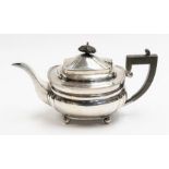 A Georgian style silver teapot, ebonised final and handle, on four ball feet, by Elkington & Co.,