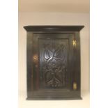 A 19th Century ebonised oak wall hanging corner cupboard, the single panel door with stylised
