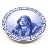 A Dutch Delft blue and white charger, painted with an Old Woman, after Rembrandt, signed to base,