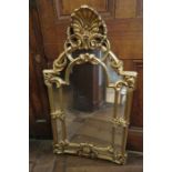 A contemporary gilt framed ornate hanging wall mirror with paneled sections.