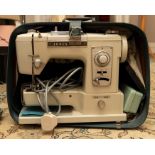 A sewing machine in a cream covering made by Jones and Co. (A Deluxe Model), electric in a blue with