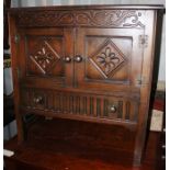 A Jacobean style oak hall unit, having two panelled doors and a drawer below, with a carved