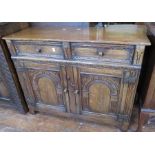 An early twentieth century oak side board with two cutlery drawers and two doors, carved details.