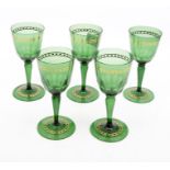 Five green glass wine glasses, with gilt banding