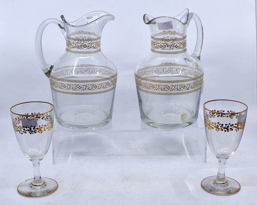 A pair of late 19th/early 20th century glass jugs, with gilt borders; and a pair of wine glasses (