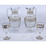 A pair of late 19th/early 20th century glass jugs, with gilt borders; and a pair of wine glasses (