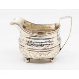 A George III silver helmet shaped cream jug, gadroon border above body later chased with flowers