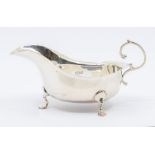 A George V silver sauceboat with wavy rim, on three scroll feet, by Barker Brothers, Birmingham,