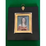 An early Victorian portrait miniature, circa 1840, a young lady, bust length wearing a crimson