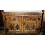 A 19th Century oak low livery cupboard. of Jacobean design, the front carved with chip carving,