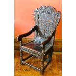 A 17th Century revival oak wainscot chair, scrolling carved top, foliage decorated panel back,