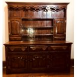 A George III oak dresser, circa 1760, moulded dental pediment above carved foliage top on three tier