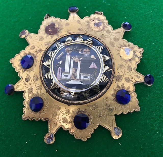 A George III gilt metal Masonic badge, the mount of sunburst form bright cut engraved foliage