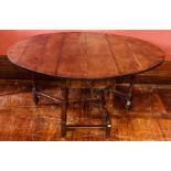 An 18th Century oak gateleg table, oval top above a single frieze drawer, flanked by two gatelegs,