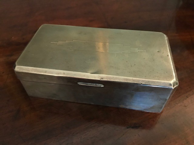 A George V silver table cigarette casket, machine engraved Art Deco design to the cover, maker