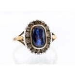 An early 20th Century sapphire and diamond 18ct gold ring, comprising a rub over set oval sapphire