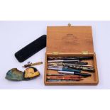 A collection of vintage fountain pens, an empty Watermans case and a cased pipe
