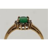 A 9ct. gold, emerald and clear stone ring, set central oval mixed cut emerald with border of clear