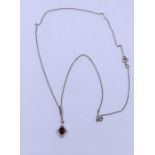 A white gold pendant , set with central ruby with similar chain