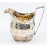 A George III silver helmet shaped cream jug, bright cut engraved decoration, central wreath