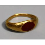 A Roman style gold and carnelian type Ring, with flared shoulders and inset oval red stone, probably