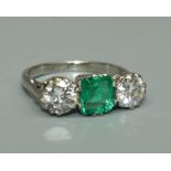 A Columbian emerald and diamond three stone ring, the central octagonal cut emerald weighing